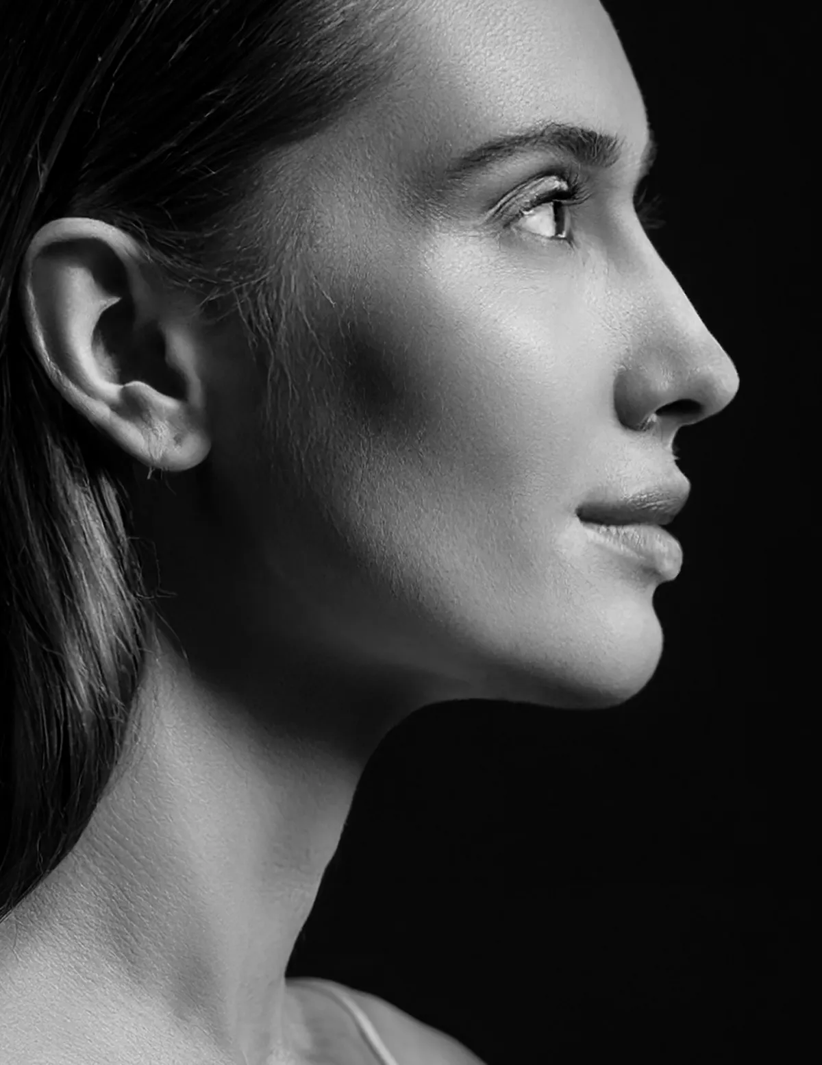 Black and white facial profile demonstrating light reflection across the cheek, jawline, and neck contour in facial rejuvenation planning